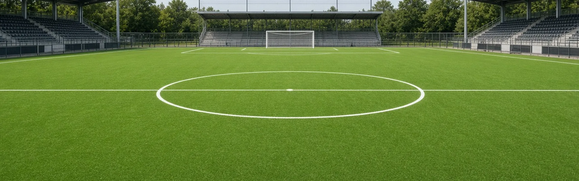 Wide low view of an empty artificial football pitch with bright green synthetic turf and white field lines